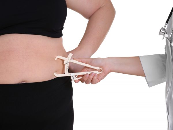 Doctor examining stout woman on white background. Weight loss concept